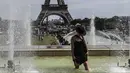 Seorang wanita mendinginkan kakinya di sebuah kolam di Trocadero Fountains dekat Menara Eiffel, Paris (22/7/2019). Warga Paris bersiap menghadapi suhu terpanas pada minggu ini ketika gelombang panas akan melanda ke Eropa utara. (AFP Photo/Alain Jocard)