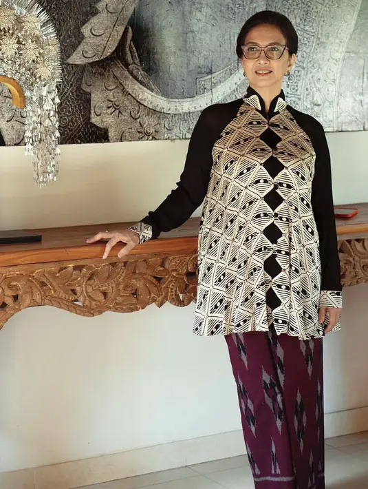 Sementara itu, sang ibunda Raline mengenakan atasan lengan panjang hitam dengan motif putih berkerah tinggi. Dipadukan kain tenun Menggah Agung warna maroon.  [@kain.menggahagung]