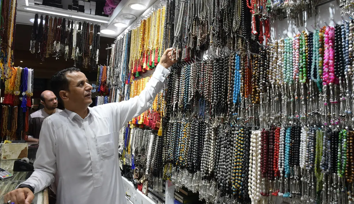 Seorang pedagang menata tasbih di tokonya di kota suci Makkah, Arab Saudi pada Selasa (6/8/2019). Puncak Ibadah haji masih beberapa hari lagi, namun jemaah sudah memborong aneka barang antara lain tasbih, baju, teko emas, kurma, sajadah, minyak wangi, pacar kuku, dan lainnya. (FETHI BELAID/AFP)