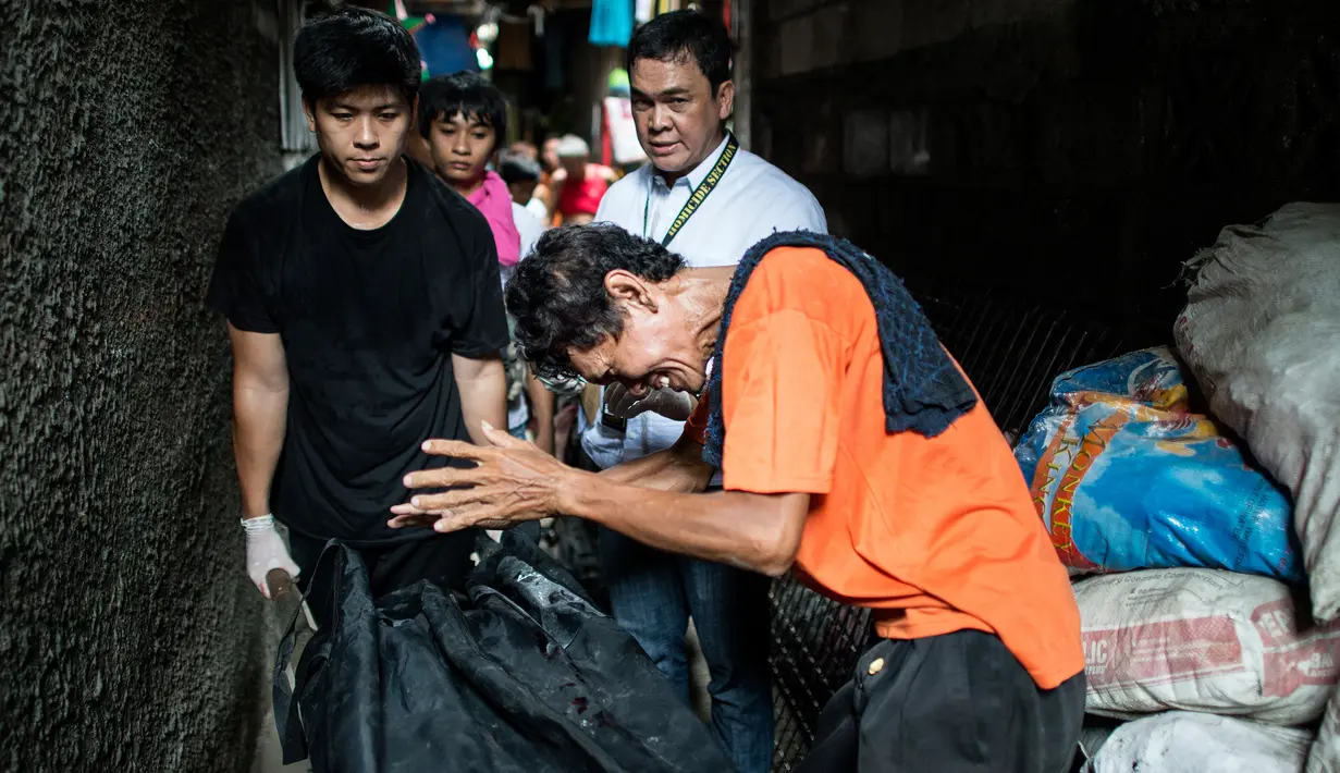 Gambar yang diambil pada 1 September 2016 menunjukkan kesedihan seorang ayah dari pengguna narkoba saat petugas mengevakuasi jasad anaknya yang diduga tewas dibunuh oleh polisi di Manila, Filipina. (AFP PHOTO/Noel CELIS)