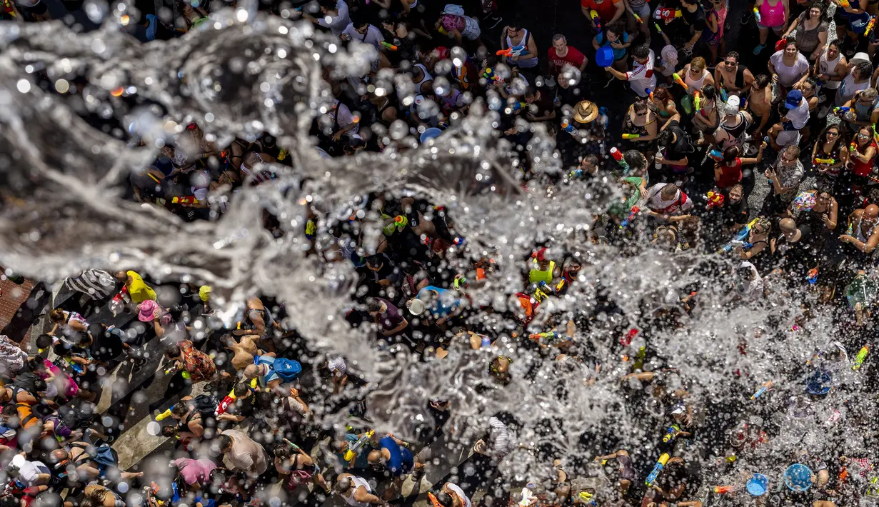 Orang-orang saling melempar air saat perang air tahunan di jalan-jalan lingkungan Vallecas, Madrid, Spanyol, 17 Juli 2022. Ribuan orang mengikuti perang air tradisional ini setelah dua tahun absen karena pandemi. (AP Photo/Manu Fernandez)