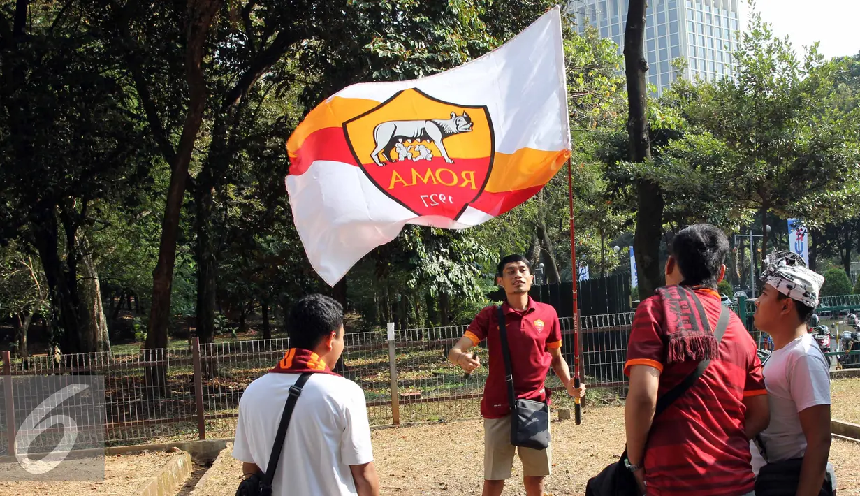Suporter mengibarkan bendera AS Roma sebelum menyaksikan tim kesayangannya bertanding di Gelora Bung Karno, Jakarta, Sabtu (25/7/2015). Tim berjuluk Giallorossi akan menggelar pertandingan intern antara skuadnya. (Liputan6.com/Herman Zakharia)