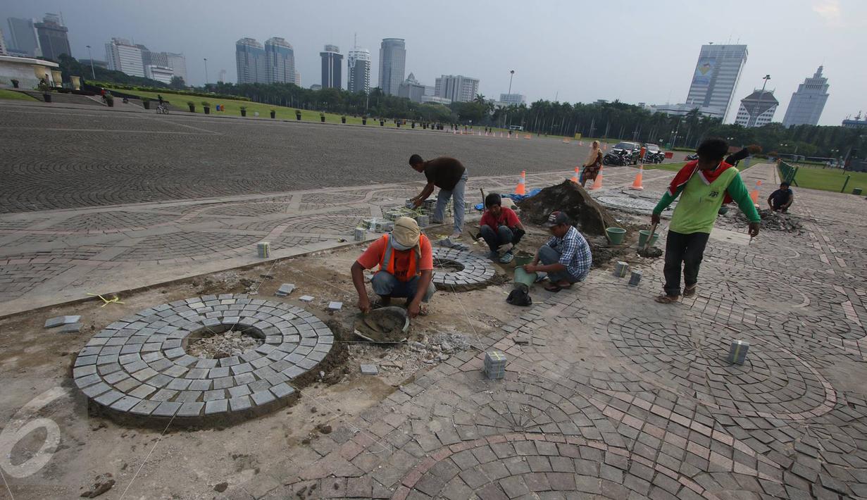 Para pekerja menyelesaikan pelataran yang rusak di kawasan Monas, Jakarta, Kamis (10/11). Hal tersebut dilakukan untuk menjaga kawasan Monas agar tetap terawat dan nyaman bagi pengunjung. (Liputan6.com/Immanuel Antonius)