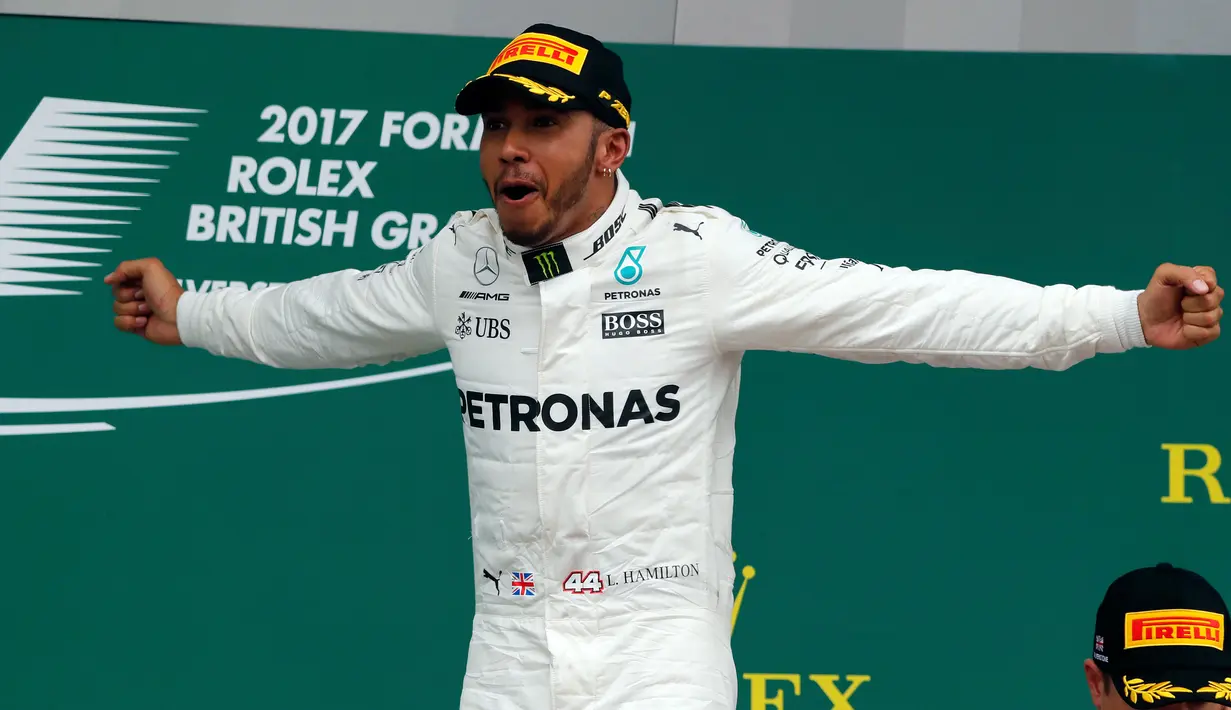 Lewis Hamilton merayakan kemenangan diatas podium setelah memenangkan GP Inggris di sirkuit Silverstone, (16/7). Kemenangan Hamilton ini sekaliguas menyamai rekor dua pebalap legendaris Formula 1 (F1), Jim Clark dan Alain Prost. (AP Photo/Frank Augstein)