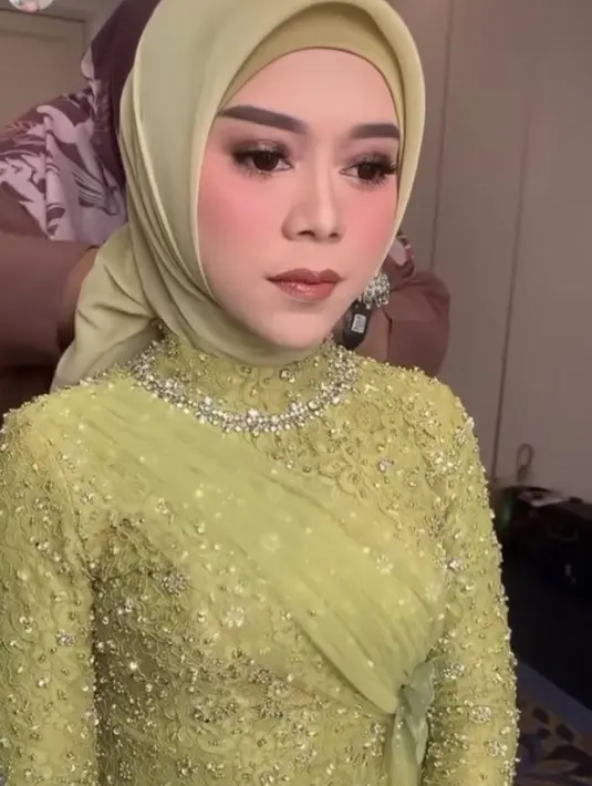 Kebaya hijau berhias borkat dan payet dibuat oleh desainer Renzila Zuardi. Dalam story Instagramnya ia mengatakan desain pakaiannya disesuaikan dengan karakter Lesti. Yang simpel namun tetap cantik, kemewahan dalam kesederhanaan. Credit: Instagram @rozanajulani