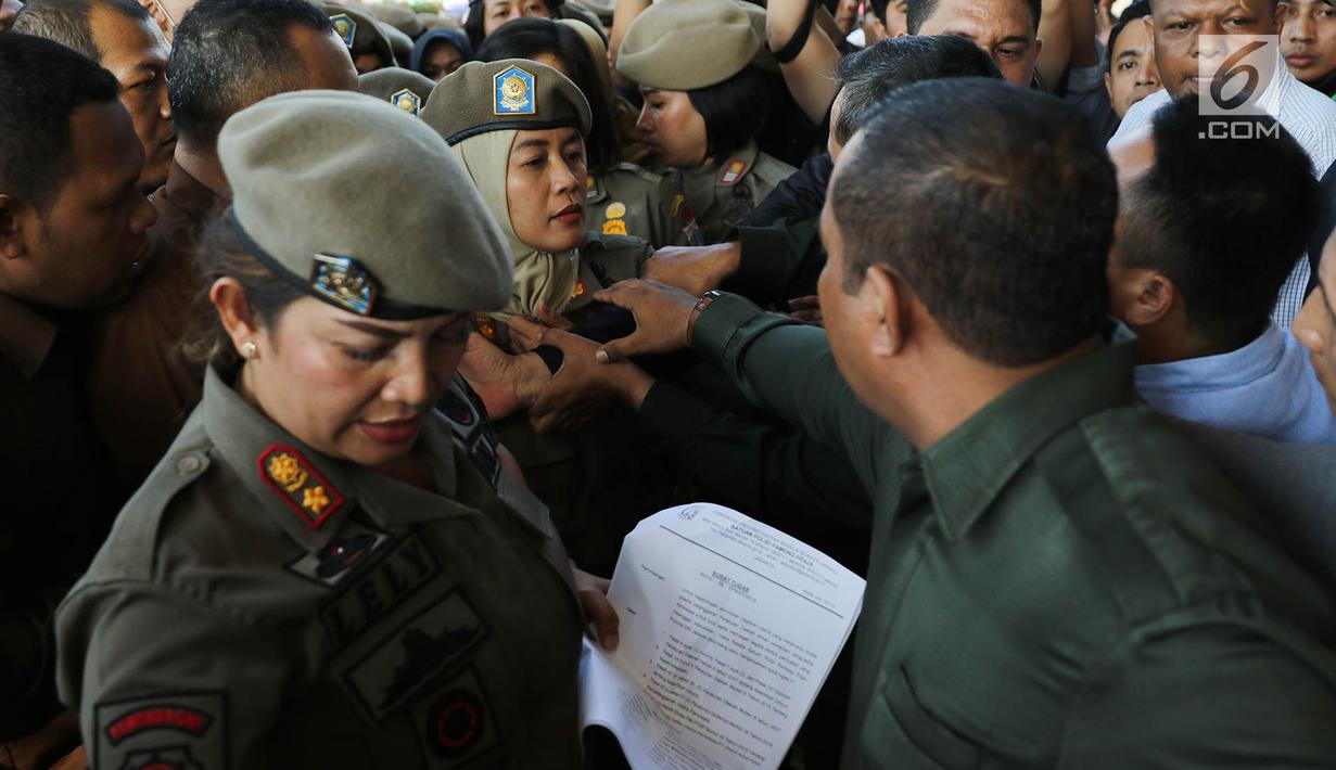 Ibu-ibu personel Satpol PP bersitegang dengan petugas keamanan di depan Hotel Alexis, Jakarta, Kamis (29/3). Pemprov DKI Jakarta resmi menutup operasi Hotel Alexis. (Liputan6.com/Immanuel Antonius)