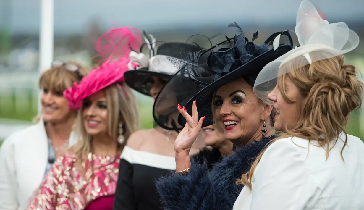 Sejumlah racegoers foto bersama selama menghadiri Festival Grand National di arena Aintree, Liverpool, Inggris, Jumat (7/4). Kehadiran racegoers memberikan nuansa tersendiri di kompetisi pacuan kuda terbesar tersebut. (AFP Photo / Oli Scarff)