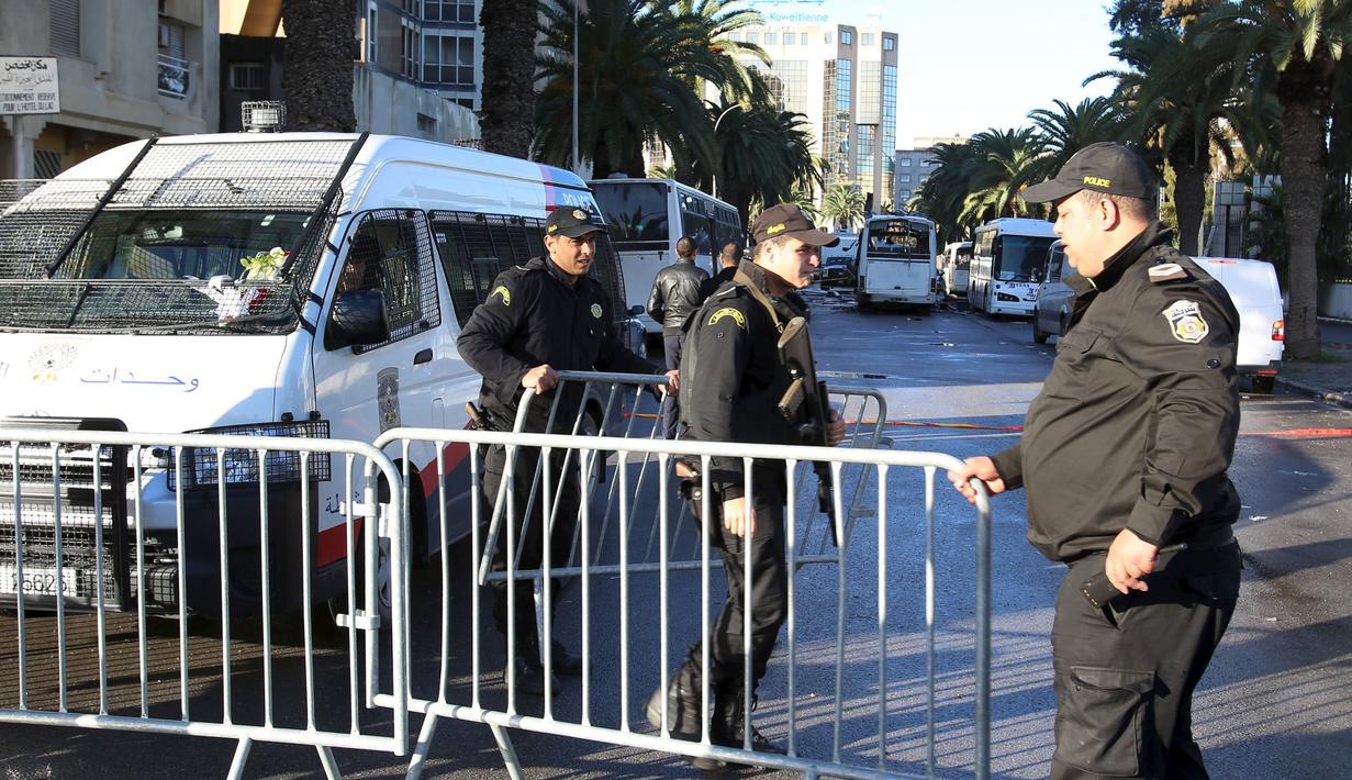 Petugas polisi saat berjaga disekitar lokasi serangan bom di Tunisia, (25/11).  Serangan bom bunuh diri ini menyerang bis pengawal presiden. (REUTERS/Zoubeir Souissi)