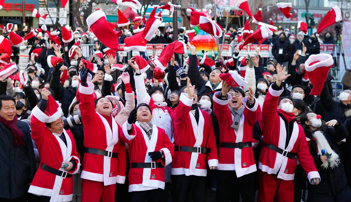 Perdana Menteri Korea Selatan Han Duck-soo (keempat dari kanan) dan para sukarelawan yang mengenakan kostum Sinterklas melemparkan topi mereka ke udara selama acara amal Natal sebelum mereka memberikan hadiah untuk orang yang kurang mampu di Seoul, Korea Selatan, 24 Desember 2022. (AP Photo/Lee Jin-man)