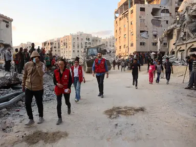 Warga bersama anggota Komite Internasional Palang Merah (ICRC) berkumpul di lokasi di mana orang-orang sedang menggali dengan ekskavator untuk mencari korban serangan Israel di antara reruntuhan bangunan di Khan Yunis, bagian selatan Jalur Gaza, pada 17 Oktober 2025. (Omar AL-QATTAA/AFP)