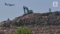 Sebuah pesawat melintas saat alat berat melakukan pengerukan sampah di TPA Rawa Kucing, Kota Tangerang, Banten, Rabu (27/9/2023). (Liputan6.com/Angga Yuniar)