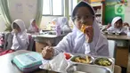 Seorang siswi sekolah dasar sedang menikmati menu makan bergizi gratis di Sekolah Dasar Negeri 01&02, Susukan, Jakarta, Senin (6/1/2025). (Liputan6.com/Herman Zakharia)