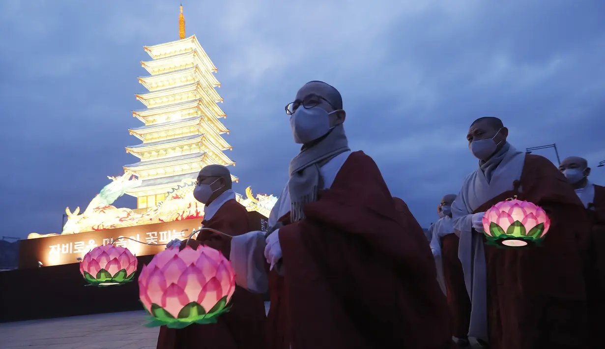 Para biksu yang mengenakan masker berjalan di sekitar menara lentera berbentuk pagoda saat merayakan ulang tahun Buddha di Gwanghwamun Plaza, Seoul, Korea Selatan, Kamis (30/4/2020). Ulang tahun Buddha kali ini dirayakan di tengah pandemi virus corona COVID-19. (AP Photo/Ahn Young-joon)