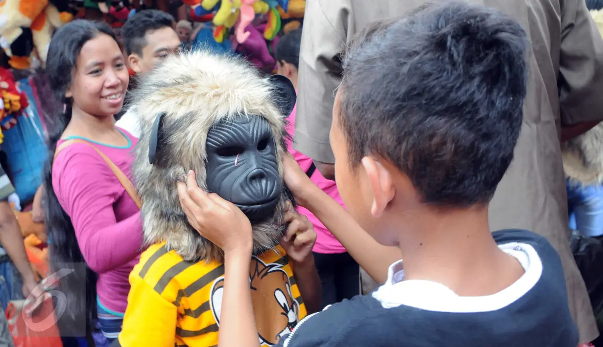 Sejumlah anak mencoba topeng yang dijajakan oleh para pedagang di Ragunan, Jakarta, Minggu (27/12/2015). Pedagang mengaku omset penjualan pada Libur Natal kali ini melonjak 3x lipat dari pada biasanya. (Liputan6.com/Helmi Afandi)