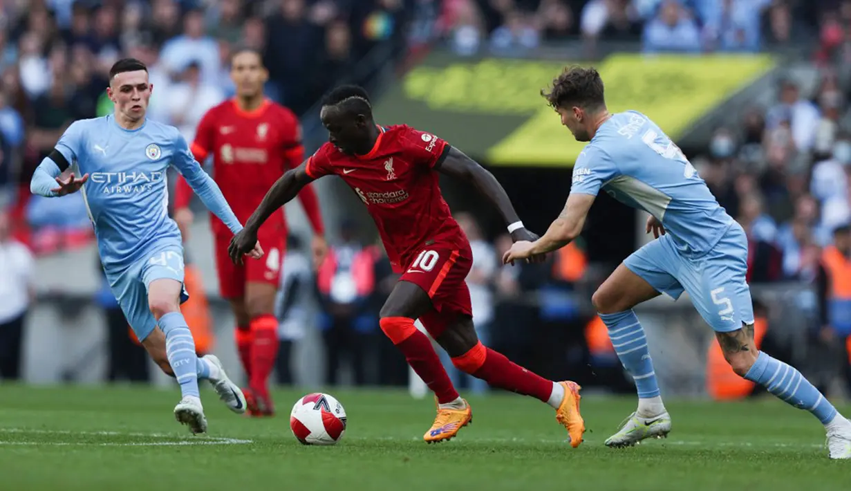 Pemain Liverpool Sadio Mane (tengah) berebut bola dengan pemain Manchester City Phil Foden (kiri) John Stones (kanan) pada pertandingan sepak bola semifinal Piala FA di Stadion Wembley, London, Inggris, 16 April 2022. Liverpool menang 3-2. (Adrian DENNIS/AFP)