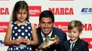 Penyerang Barcelona, Luis Suarez bersama kedua anaknya Delfina dan Benjamin, berpose dengan trofi Sepatu Emas Eropa 2016 selama penghargaan Golden Shoe atau sepatu emas untuk tahun 2016 di Barcelona, Spanyol (20/10). (REUTERS/Albert Gea)