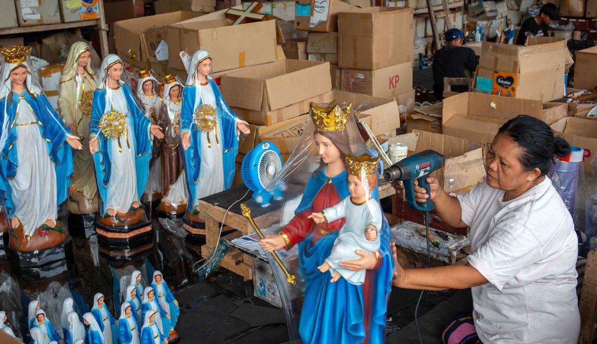 Bahkan peningkatan pesanan pembuatan patung rohani keagamaan Kristen bisa mencapai 200 persen. Tampak dalam foto, seorang pekerja membungkus patung keagamaan Kristen di bengkel kerajinan Studio Malta Jaya di Bantul, Yogyakarta, pada Kamis 18 Desember 2025. (DEVI RAHMAN/AFP)