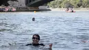 Mengenakan wetsuit dan kacamata renang, Hidalgo terjun ke sungai dekat Balai Kota yang megah dan Katedral Notre Dame. (JOEL SAGET / POOL / AFP)
