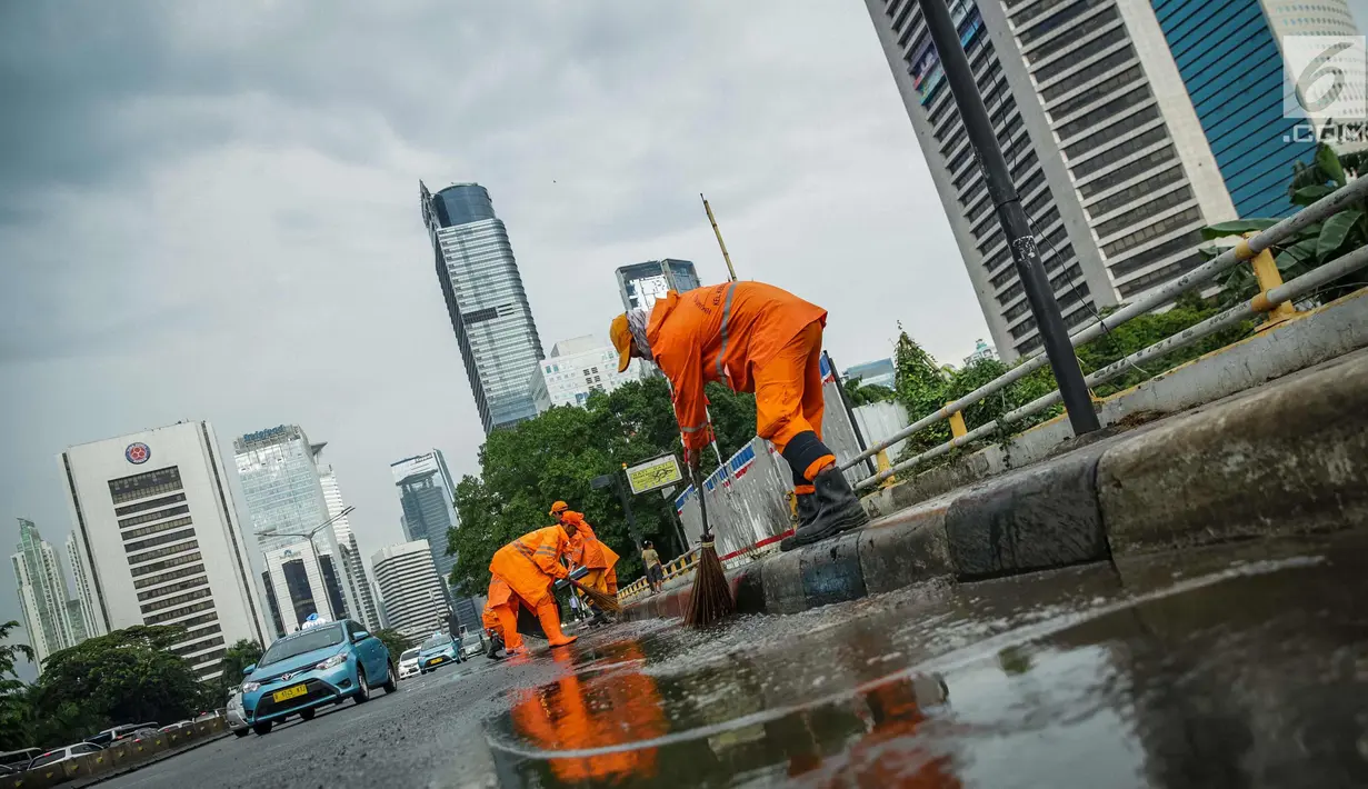 Petugas Dinas Kebersihan membersihkan genangan air usai hujan di kawasan jalan Sudirman, Jakarta, Rabu (22/11). Buruknya sistem drainase membuat petugas membersihkan genangan setiap kali hujan, meski dengan peralatan seadanya. (Liputan6.com/Faizal Fanani)