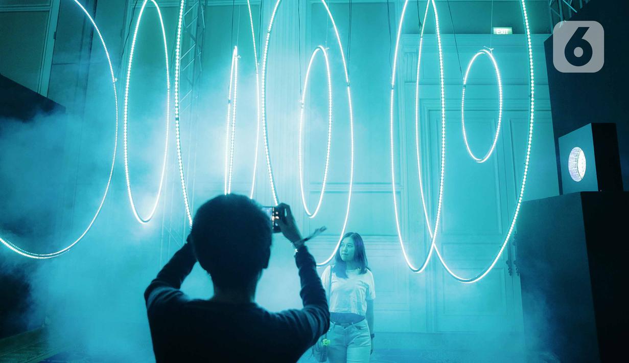 Pengunjung berpose saat mengunjungi pameran seni berbasis teknologi berwujud sorotan cahaya futuristik 'Wave of Tomorrow' di Jakarta, Sabtu (21/12/2019). Pameran seni Wave of Tomorrow' menghadirkan 14 karya seni media baru dari 13 kreator Tanah Air dan internasional. (Liputan6.com/Faizal Fanani)