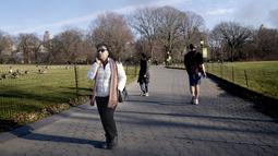 Pejalan kaki melewati Great Lawn di pusat Central Park, di wilayah Manhattan, New York, Senin (30/1/2023). Terakhir kali butuh waktu lama sebelum salju bertahan di tanah pada musim dingin adalah tahun 1973, ketika warga New York harus menunggu hingga 29 Januari. (AP Photo/John Minchillo)