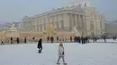 Salju yang menumpuk di atas permukaan jalan yang membeku membuat akses transportasi menjadi licin. Tampak dalam foto, para pengunjung melewati Chateau de Versailles yang diselimuti salju, di Versailles, luar Kota Paris pada Selasa 6 Januari 2026. (GEOFFROY VAN DER HASSELT/AFP)