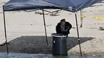 Seorang pejabat berdiri di samping tong tempat mayat ditemukan di Malibu Lagoon State Beach, California pada 31 Juli 2023.(AFP/Robyn Beck)