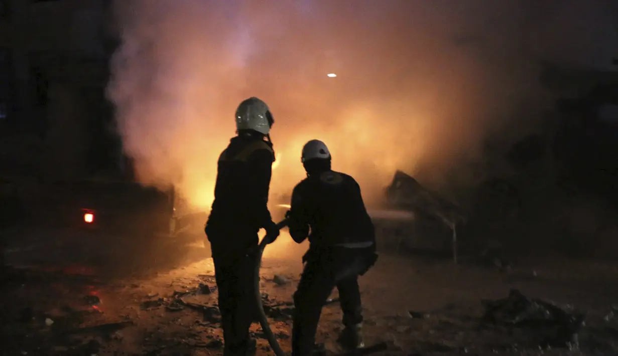 Sejumlah relawan White Helmets memadamkan api setelah pengeboman Kantor Ajnad al-Koukaz di Idlib, Suriah, Minggu, (7/1). Ajnad al-Koukaz merupakan kelompok militan yang kebanyakan dari Kaukasus dan Rusia. (Syrian Civil Defense White Helmets via AP)