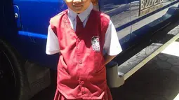 Angeline saat mengenakan seragam sekolah berwarna merah. Tak ada yang mengangka, bocah lucu dan cantik ini harus meninggal dengan cara yang tragis. (Facebook.com/Find Angeline - Bali's Missing Child)