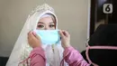 Pengantin wanita dipasangkan masker sebelum melaksanakan prosesi akad nikah di KUA Jagakarsa, Jakarta, Sabtu (6/6/2020). Pernikahan mengikuti protokol kesehatan sesuai Surat Edaran (SE) Menteri Agama Nomor 15 Tahun 2020. (Liputan6.com/Faizal Fanani)