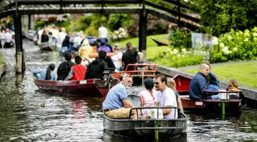 Wisatawan menaiki perahu menyusuri sungai di Giethoorn yang menjadi tujuan wisata favorit di Belanda pada 6 Agustus 2019. Mendapat julukan 'Venice of the North', kota tersebut menggunakan kanal-kanal sebagai jalan dan lalu lalang transportasi sehari-hari. (Robin van Lonkhuijsen/ANP/AFP)