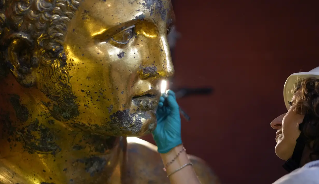 Pemulih Museum Vatikan Alice Baltera mengerjakan patung perunggu Hercules, di Aula Bundar Museum Vatikan, Kamis, 11 Mei 2023. (AP Photo/Andrew Medichini)