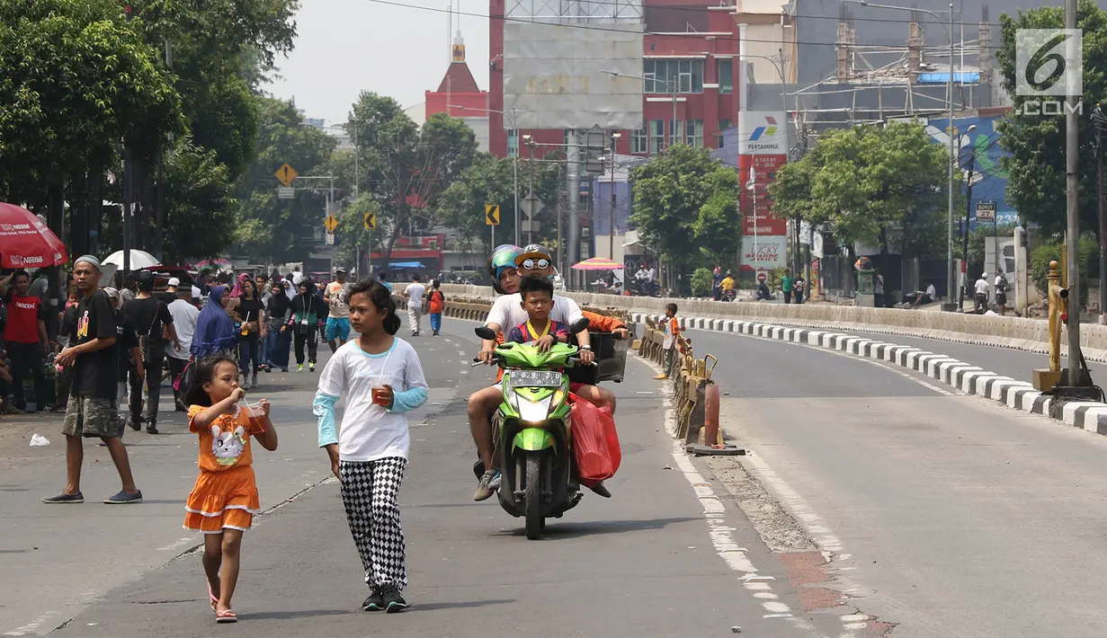 Pengendara motor melintasi arena Car Free Day (CFD) di Jalan Warung Jati Barat, Jakarta, Minggu (17/9).  Beberapa pengendara motor terlihat bebas menerabas jalan yang dipenuhi orang yang sedang berolahraga dan berjualan. (Liputan6.com/Immanuel Antonius)