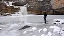 Pengunjung memancing di kolam air terjun Mirusha yang membeku, di Lapceve, Kosovo, Senin (9/1). Cuaca bersuhu mencapai minus 20 derajat celcius membuat Air Terjun Mirusha dan kolam membeku. (AFP Photo/Armend Nimani)