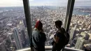 Pengunjung menikmati pemandangan Kota Manhattan dari ruangan observatorium di lantai 102 Gedung Empire State yang baru direnovasi di New York (10/10/2019). Dibuka untuk umum pada 12 Oktober, ruang observatorium ini berjarak 1.250 kaki di atas permukaan jalan. (AFP Photo/Drew Angerer)