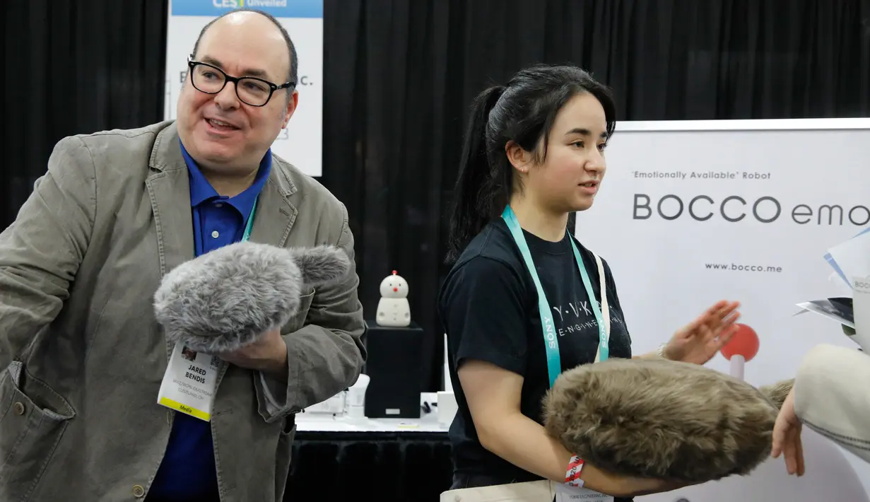 Pengunjung memegang robot Qoobo saat pameran teknologi CES 2020 di Las Vegas, Amerika Serikat, Minggu (5/1/2020). Qoobo adalah robot terapi berbentuk bantal dengan ekor. (AP Photo/John Locher)