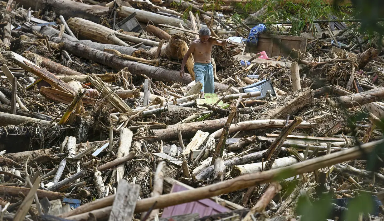 Seorang warga desa terdampak banjir bandang berjalan di antara tumpukan kayu di Desa Tukka, Tapanuli Tengah, Sumatera Utara, pada 2 Desember 2025. Banjir bandang dan tanah longsor yang melanda Kabupaten Tapanuli Tengah sejak 25 November 2025 telah menelan korban. Ada dua desa yang paling parah terdampak, yakni Desa Tukka dan Desa Tanah Bolon. (YT HARIONO/AFP)