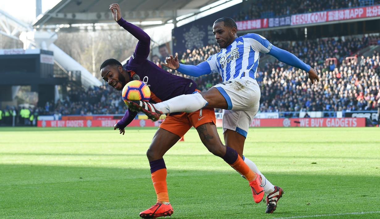 Gelandang Man City, Raheem Sterling dijegal pemain Huddersfield, Puncheon pada laga lanjutan Premier League yang berlangsung di stadion John Smith, Huddersfield, Minggu (20/1). Manchester City menang 3-0 atas Huddersfield. (AFP/Paul Ellis)