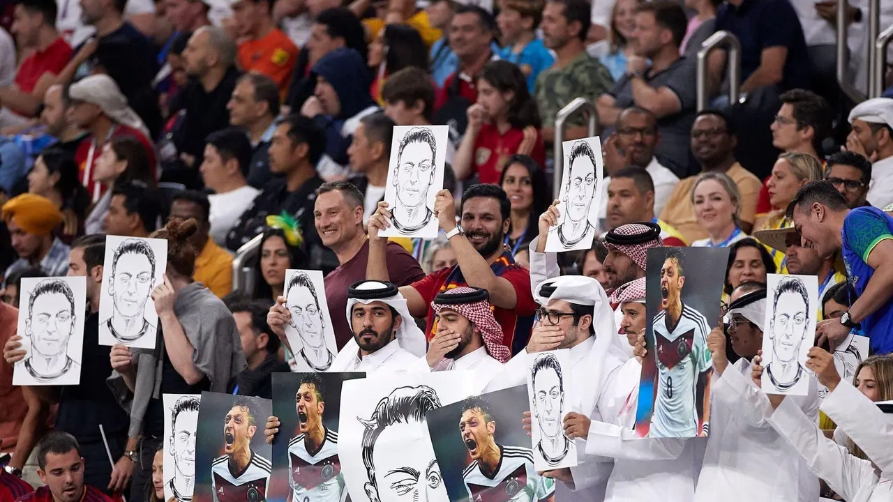Penonton Qatar memegang foto Mesut Ozil (Foto: Twitter @granitacademy)