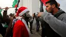 Pengunjuk rasa berkostum Santa Claus berhadapan dengan petugas penjaga perbatasan saat aksi di desa Tepi Barat Bilin dekat Ramallah, Jumat (23/12). Pengunjuk rasa menentang pembangunan tembok pembatas di Israel. (REUTERS/Mussa Issa Qawasma)