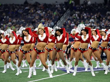 Sejumlah pemandu sorak (cheerleader) Cowboys Dallas berkostum santa claus menghibur penonton saat tim Cowboys Dallas istirahat pada pertandingan Seattle Seahawks di AT & T Stadium, Texas (24/12). (AFP / Getty Images / Tom Pennington)