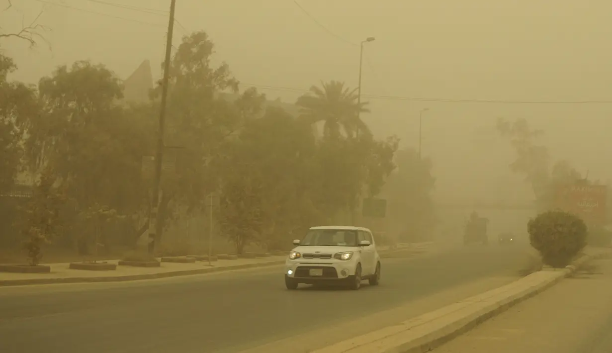 <p>Pengemudi memasang lampu kabut mobil mereka saat mereka mengemudi selama badai pasir Musim Semi melalui ibukota Irak, Baghdad (5/5/2022). Irak kembali diselimuti lapisan jingga tebal karena mengalami serangkaian badai debu terbaru yang semakin sering terjadi. (AFP/Sabah Arar)</p>