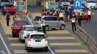 Petugas mengarahkan kendaraan berplat genap berputar balik di Gerbang Tol Bekasi Barat 1, Bekasi, Jawa Barat, Selasa (13/3). Hari kedua penerapan ganjil genap, masih banyak kendaraan berputar balik di gerbang tol tersebut. (Liputan6.com/Arya Manggala)
