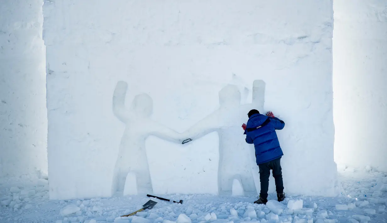 Seorang seniman mengukir patung es raksasa simbol persahabatan di Snow Land, PyeongChang, Korea Selatan, Senin (5/2). (Brendan Smialowski/AFP)