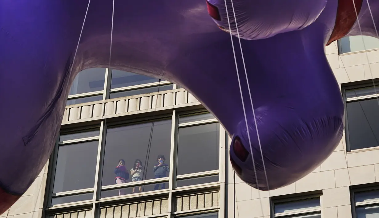 Anak-anak muda menonton dari jendela saat balon dari Macy's Thanksgiving Day Parade lewat di New York, Amerika Serikat, 25 November 2021. Macy's Thanksgiving Day Parade kembali sepenuhnya setelah dirundung pandemi COVID-19 tahun lalu. (AP Photo/Seth Wenig)