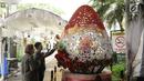 Warga melihat hiasan telur paskah yang ada pada dekorasi telur paskah raksasa di Gereja Katedral, Jakarta, Minggu (4/1). Hiasan pada telur telur paskah tersebut mewarnai perayaan Paskah di Gereja Katedral. (Liputan6.com/Helmi Fithriansyah)
