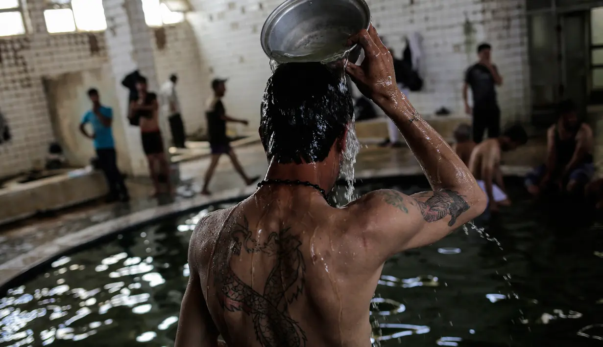 Pengunjung mengguyur kepala dengan air hangat dari belerang di Hamam Alli, Mosul, Irak, (27/4). Hammam Al Alil, yang berarti kamar Mandi Bagi Yang Sakit dalam bahasa Arab, kini opuler di kalangan pengungsi dan pasukan Irak. (AP Photo/Bram Janssen)
