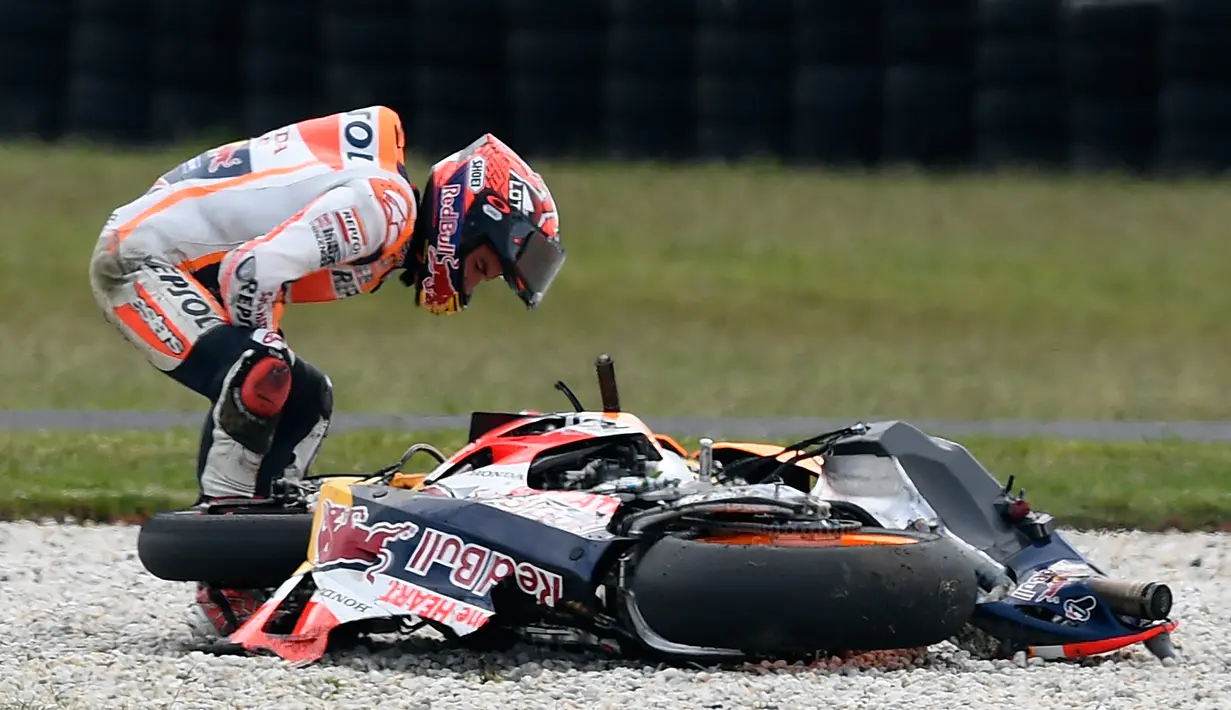 Marc Marquez bersama motornya setelah terjatuh saat balapan MotoGP Australia di Sirkuit Philip Island, Australia (21/10). Marquez terjatuh di lap sembilan dan tidak bisa melanjutkan lomba. (AFP/Jerey Brown)