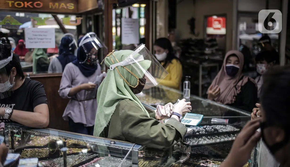 Pedagang mengenakan masker dan pelindung wajah saat melayani pembeli di  Pasar Kebayoran Lama, Jakarta Selatan, Senin (22/6/2020). Pasar Kebayoran Lama kembali buka setelah sebelumnya tutup selama tiga hari sejak 18 Juni 2020 akibat 14 pedagang positif COVID-19. (Liputan6.com/Faizal Fanani)