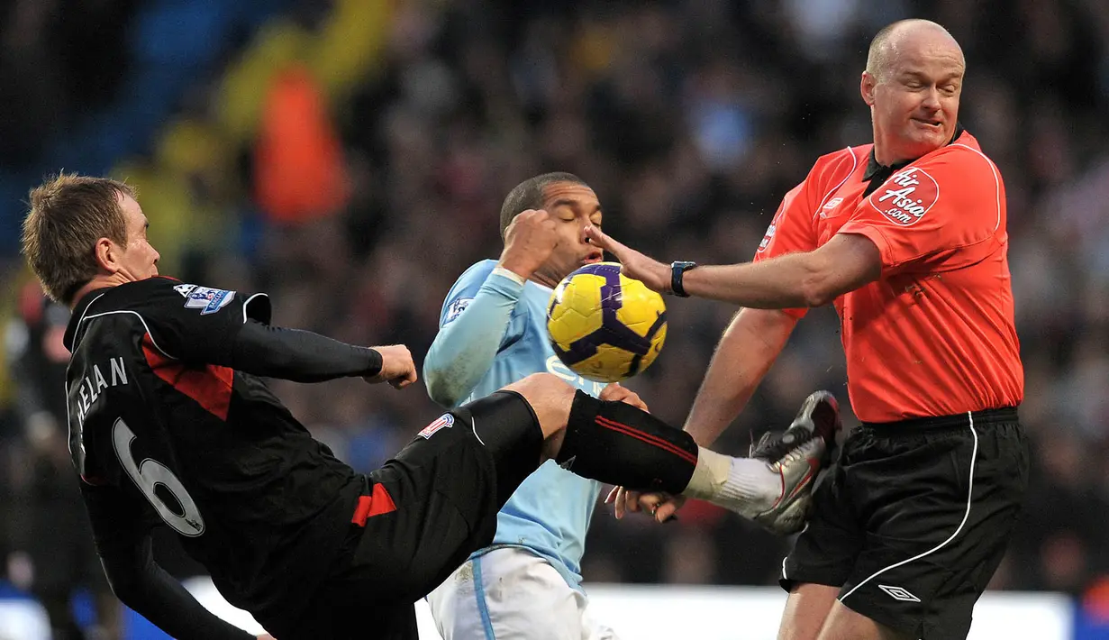 Duel gelandang Manchester City, Nigel de Jong, dengan gelandang Stoke, Glenn Whelan, hampir membuat wasit Lee Mason terkena tendangan pada laga boxing day Premier League di Stadion City Of Manchester, Inggris, Sabtu (26/12/2009). (AFP/Andrew Yates)